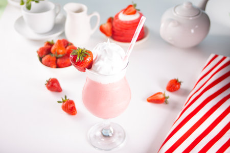 Glass of strawberry milkshake or smoothie with paper straw on yellow background. Summer healthy vitamin beverage, diet or vegan foodの写真素材