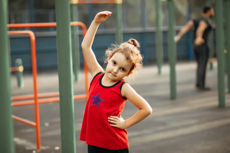 Cute kid girl doing gymnastic exercises outdoor in a park.の写真素材