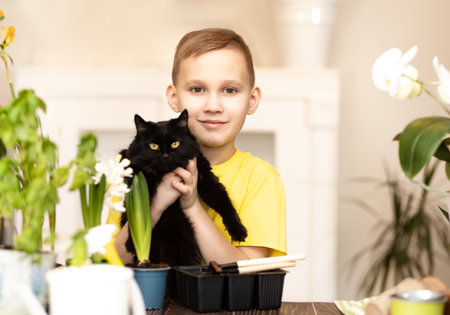 home gardening. Little kid boy holding black cat and helping to care for home plants, green environment at home, planting seedsの写真素材