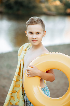 Happy child teen boy with yellow swimming ring lifebuoy near by river, lake or pond. vacation conceptの写真素材
