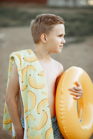 Happy child teen boy with yellow swimming ring lifebuoy near by river, lake or pond. vacation conceptの写真素材