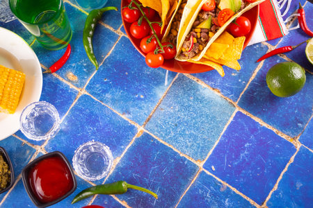Mexican tequila shots with lime and hot red chili with traditional food corn tacos on the blue backgroundの写真素材