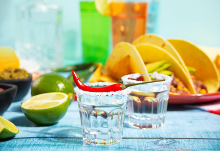 Mexican tequila shots with lime and hot red chili with traditional food corn tacos on the backgroundの写真素材