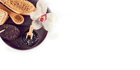 Spa treatment concept. Flat lay composition with massage brushes, pumice stone, black salt, orchid flowerの写真素材