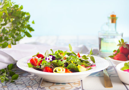 Spring healthy fresh salad with green, edible flowers pansies viola and strawberries.の写真素材