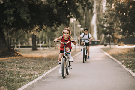 Two little boy and girl cyclists riding their bikes and enjoy having fun. Kid outdoors sport summer activity.の写真素材