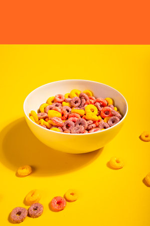 Bowl of colorful cereal corn rings on yellow table. Breakfast concept.の写真素材