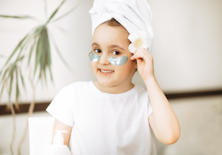 Funny little girl with towel on her head looking at camera with eye mask. Spa, healthcare, morning routine conceptの写真素材