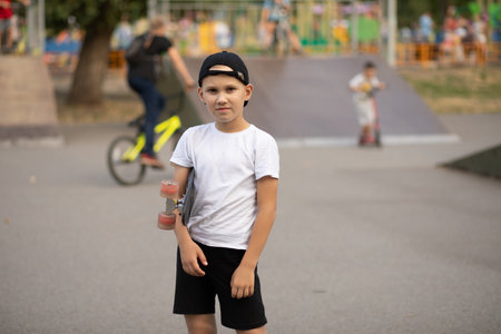Cute kid boy child standing in a special area in skatepark and holding skateboard. Summer sport activity concept. Happy childhood.の写真素材