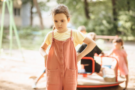 Upset lonely bullied little kid girl looking away feels abandoned, sad alone preschool child in kindergarten or playground.の写真素材