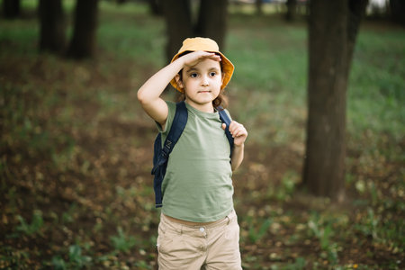 Cute little girl wearing a scout uniform standing in a forest. Young kid exploring nature. Outdoor activity for childrenの写真素材