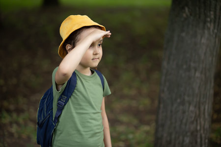 Cute little girl wear scout uniform standing in a forest. Young kid exploring nature. Outdoor activity for childrenの写真素材