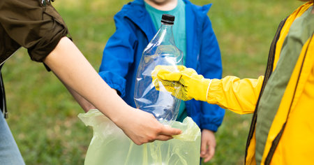 Mom and son and daughter picking up trash plastic bottles in the park. Volunteer concept. Ecology, recycling concept. Earth day 22 April. World Environment Day. Save planetの写真素材
