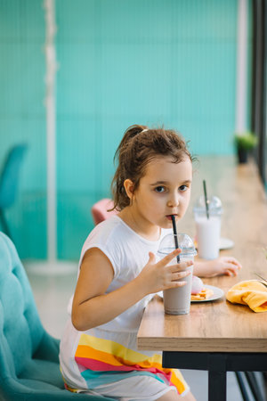 Cute girl drinking milkshake in cafe and having fun. Retro style.の写真素材