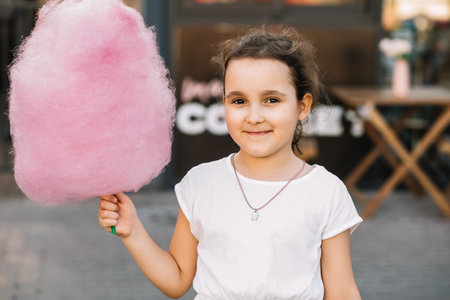Cute little girl eating cotton candy. Happy childhood. Summer holidays concept.の写真素材