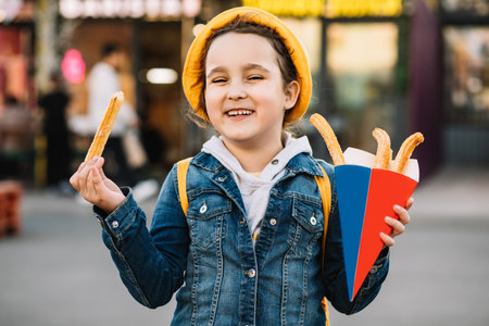 Cute little girl eating traditional Spanish treat street food churros. Food delivery or take away food conceptの写真素材