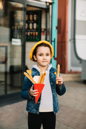 Cute little girl eating traditional Spanish treat street food churros.の写真素材