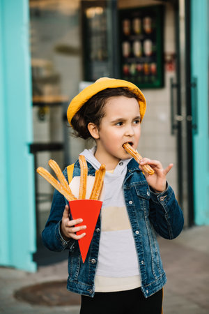 Cute little girl eating traditional Spanish treat churros.の写真素材