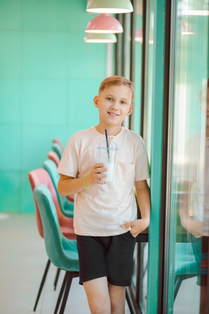 Teenager kid boy drinking milkshake in retro style cafe and having funの写真素材