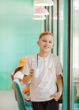 Teenager kid boy drinking milkshake in retro style cafe and having funの写真素材