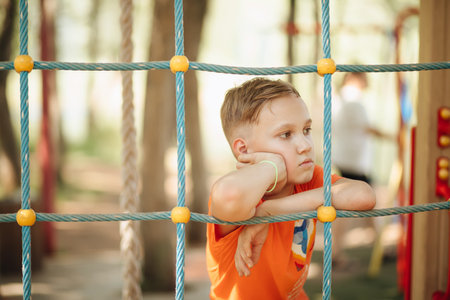 Boy with a contemplative expression on playground.の写真素材