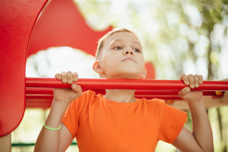 Kid teenager boy doing pull ups on horizontal bar. Active kid exercising and doing pull ups on metal...