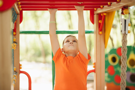 Kid teenager boy doing pull ups on horizontal bar. Active kid exercising and doing pull ups on metal sports equipmentの写真素材