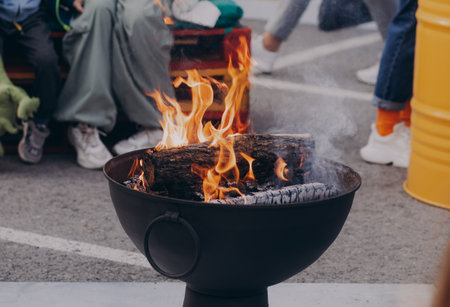 Gathering of people around a striking iron fire pit (fire ring) burning wood.の写真素材