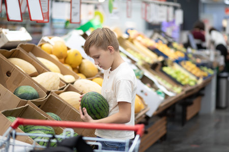 Kid teenager boy shopping for fresh fruits and vegetables in supermarket.の写真素材