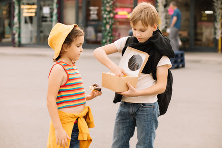 Kids eating colorful sweet and tasty donuts. Children snacking on food outdoors.の写真素材