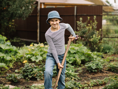 Boy working in garden. Teenager digging soil with shovel. Countryside farm.の写真素材