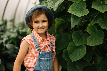 Cute kid girl standing in greenhouse. Countryside farm.の写真素材
