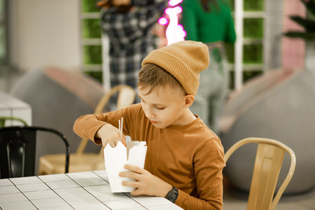 Kid teen child boy eating ramen noodle wok with chopsticks in food court. Lunch timeの写真素材
