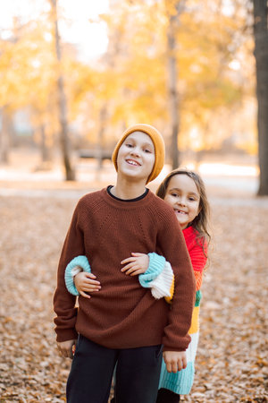 Cute little girl and boy siblings hugging in the autumn park. Children have fun outdoors. Brother and sister resting. Support and time with family.の写真素材