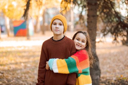 Cute little girl and boy siblings hugging in the autumn park. Children have fun outdoors. Brother and sister resting. Support and time with family.の写真素材