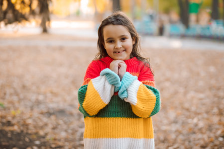 Fall season autumn landscape sunny day. Trees and leaves background. Cute little girl standing in a park outdoorの写真素材