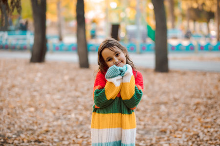 Fall season autumn landscape sunny day. Trees and leaves background. Cute little girl standing in a park outdoorの写真素材