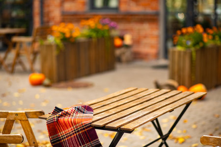 Cafe patio with empty wooden table and chair is set up in a autumn decoration with pumpkins, leaves and flowers. Fall aesthetic.の写真素材