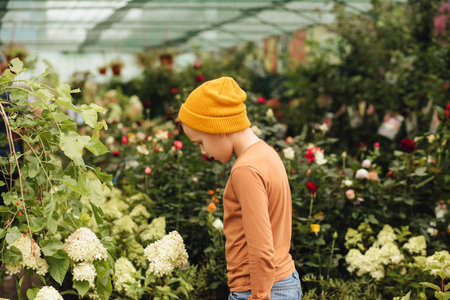 Kid teenager boy buying flowers in market. Choosing plants in a local garden centerの写真素材