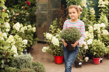 Little cute girl buying flowers in market. Choosing plants in a local garden centerの写真素材