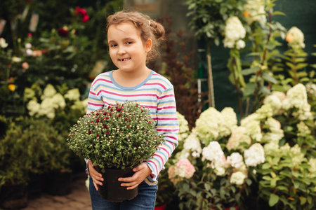 Little cute girl buying flowers in market. Choosing plants in a local garden centerの写真素材