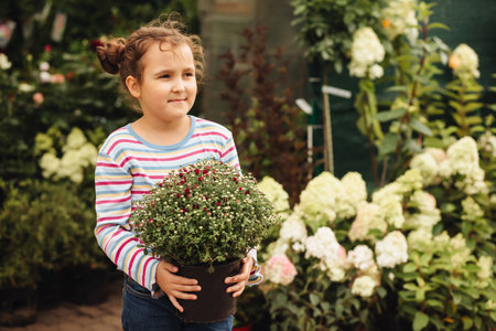 Little cute girl buying flowers in market. Choosing plants in a local garden centerの写真素材