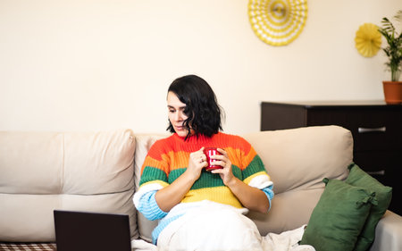 Mature woman using laptop sitting on a sofa at home.の写真素材