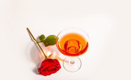 Glass of red wine with red rose on the white background. Romantic date conceptの写真素材