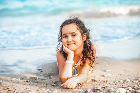 Cute little girl lying on the seashore at the beach in summer. Playful active kid. Holiday vacation with childrenの写真素材