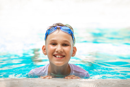 Happy kid boy playing in outdoor swimming pool at sunny day. Active vacation and healthy lifestyle. Happy summertimeの写真素材