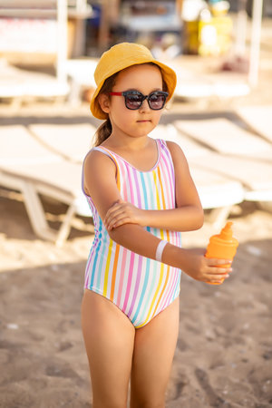 Cute little girl applying sunscreen at the beach in summer. Holiday vacation with childrenの写真素材