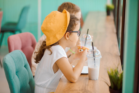 Cute girl and teenager boy eat waffles with ice cream and drinking milkshake in cafe and having fun. Retro styleの写真素材