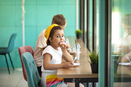 Cute girl and teenager boy eat waffles with ice cream and drinking milkshake in cafe and having fun.の写真素材