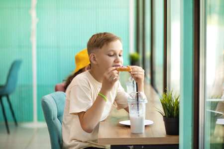 Cute girl and teenager boy eat waffles with ice cream and drinking milkshake in cafe and having fun. Retro styleの写真素材